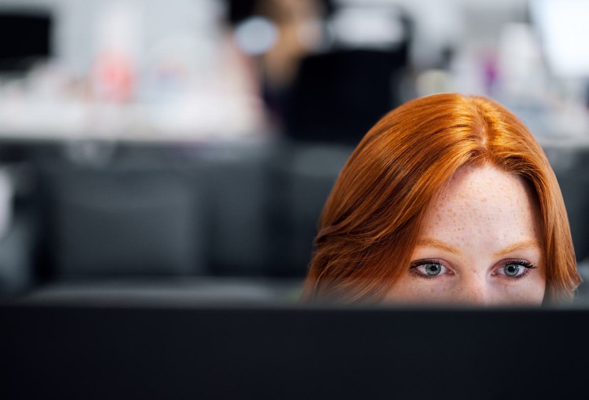 Close-up of a red-haired woman working on a computer.